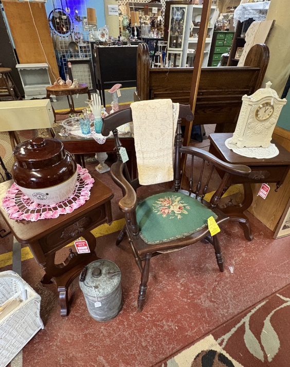 Charming antique furniture display featuring a vintage floral needlepoint chair, Victorian-style end tables, ceramic crock, and ornate mantle clock—perfect for collectors and home décor enthusiasts